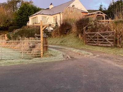 a house with a wooden gate and a fence at Shepherds Hut-hot tub hire-dog friendly-views in Dumfries