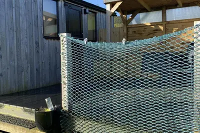 a chain link fence in front of a house at Shepherds Hut-hot tub hire-dog friendly-views in Dumfries