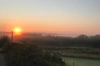 a sunset with the sun rising over a field at Shepherds Hut-hot tub hire-dog friendly-views in Dumfries