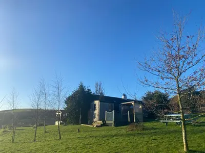 a house in the middle of a field at Shepherds Hut-hot tub hire-dog friendly-views in Dumfries