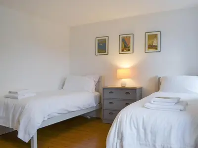 a bedroom with two beds and a night stand with a lamp at Holly Cottage in Cockermouth