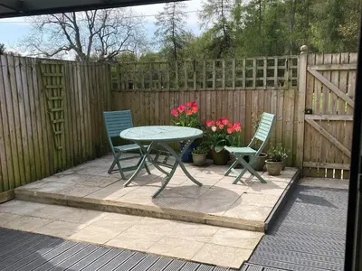 a patio with a table and two chairs and a fence at Holly Cottage in Cockermouth