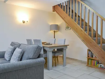 a living room with a couch and a table and stairs at Holly Cottage in Cockermouth