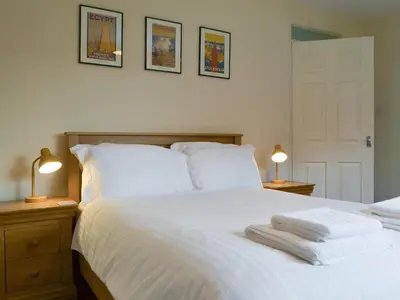 a bedroom with a white bed with two towels on it at Holly Cottage in Cockermouth