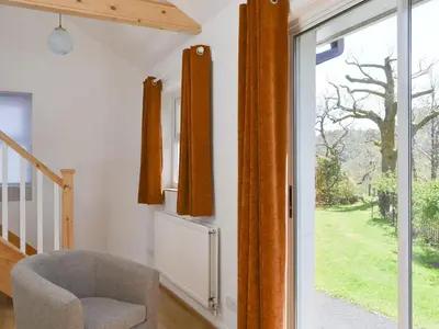 a room with a chair and a sliding glass door at Langdale Cottage in Chapel Stile