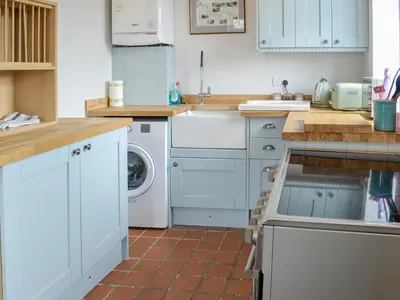 a kitchen with white cabinets and a washer and dryer at Old Reading Room in Cotehill
