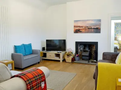 a living room with a fireplace and a tv at Kirklauchline Cottage in Portpatrick