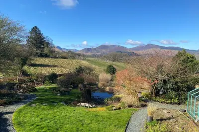 a garden with a river and mountains in the background at The Lookout Keswick in Keswick