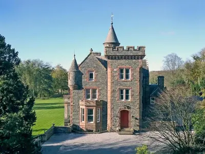 an old stone house with two towers on top at Machermore Castle in Newton Stewart