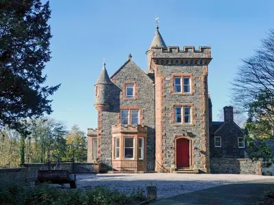 an old stone house with a red door at Machermore Castle in Newton Stewart