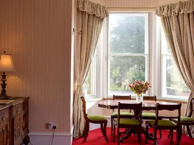 a dining room with a table and chairs and a window at Machermore Castle in Newton Stewart