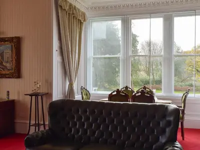 a living room with a couch and a large window at Machermore Castle in Newton Stewart