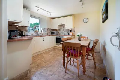 a kitchen with a table and chairs and a clock at Meadow View Chapel Stile in Chapel Stile