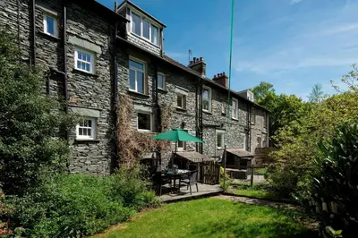 a building with a table and an umbrella in the yard at Meadow View Chapel Stile in Chapel Stile