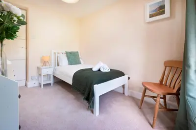 a bedroom with a white bed and a chair at Meadow View Chapel Stile in Chapel Stile