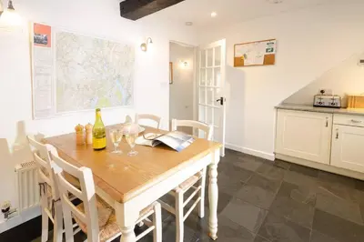 a kitchen with a wooden table with chairs and a map at Pippins, Elterwater in Chapel Stile