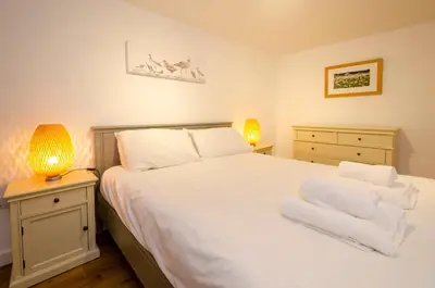 a bedroom with a large white bed with two lamps at 12 Thrang Brow, Chapel Stile in Chapel Stile