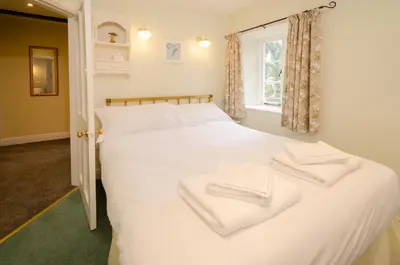a bedroom with a white bed with towels on it at 2 Bridge Syke, Elterwater in Chapel Stile