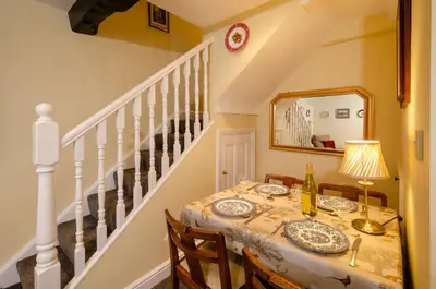 a dining room with a table and a mirror at 2 Bridge Syke, Elterwater in Chapel Stile