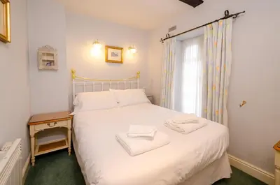 a bedroom with a white bed and a window at 2 Bridge Syke, Elterwater in Chapel Stile