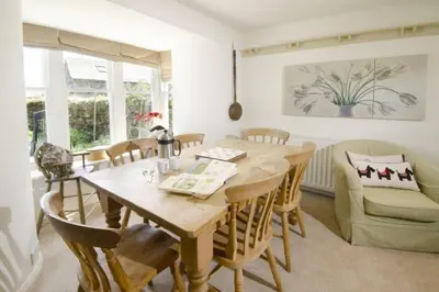 a dining room with a wooden table and chairs at Barnhowe, Elterwater in Chapel Stile