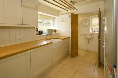a kitchen with white cabinets and a sink at Barnhowe, Elterwater in Chapel Stile