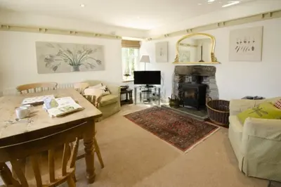 a living room with a table and a fireplace at Barnhowe, Elterwater in Chapel Stile
