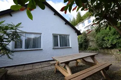 a wooden picnic table in front of a white house at Christmas Cottage in Chapel Stile