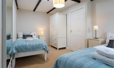 a bedroom with two beds and a mirror at Christmas Cottage in Chapel Stile