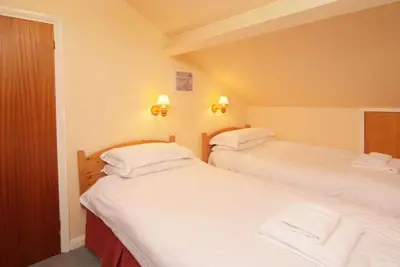 two beds in a hotel room with white sheets at Church Bank in Chapel Stile