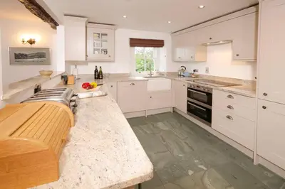 a kitchen with white cabinets and a wooden counter top at End Cottage, Chapel Stile in Chapel Stile
