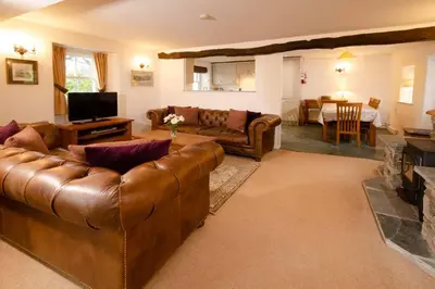 a living room with a leather couch and a television at End Cottage, Chapel Stile in Chapel Stile