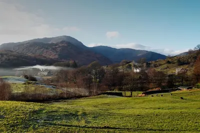 a green field with mountains in the background at Farra Grain, Little Langdale in Little Langdale