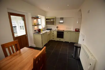 a kitchen with a wooden table and a kitchen with a counter top at Farra Grain, Little Langdale in Little Langdale