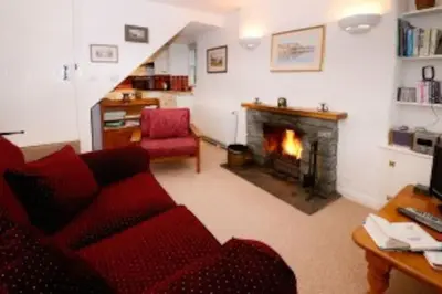 a living room with a red couch and a fireplace at Inglewood Cottage, Chapel Stile in Chapel Stile