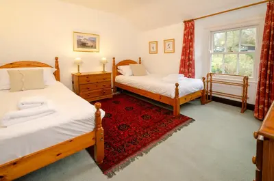 a bedroom with two beds and a red rug at Nans, Elterwater in Chapel Stile