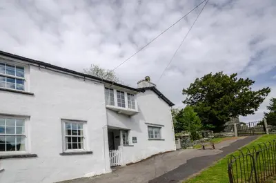 a white house with a fence in front of it at Priest End, Chapel Stile in Chapel Stile