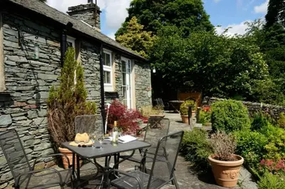 a table and chairs in front of a stone house at Rosegate Cottage, Elterwater in Elterwater