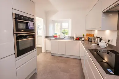 a kitchen with white cabinets and black appliances at Rosegate House, Elterwater in Elterwater