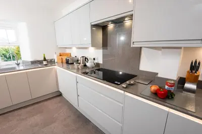 a kitchen with white cabinets and stainless steel appliances at Rosegate House, Elterwater in Elterwater