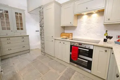 a kitchen with white cabinets and a stove top oven at Speddy Cottage, Chapel Stile in Chapel Stile