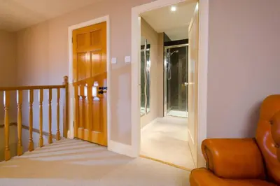 a hallway with a door and a chair in a house at The Eltermere Old Barn, Elterwater in Elterwater