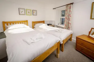 a bedroom with two beds with white sheets and a dresser at The Old Post Office, Chapel Stile in Chapel Stile