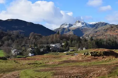 a village in a mountain valley with snow capped mountains at The Stables, Elterwater in Elterwater