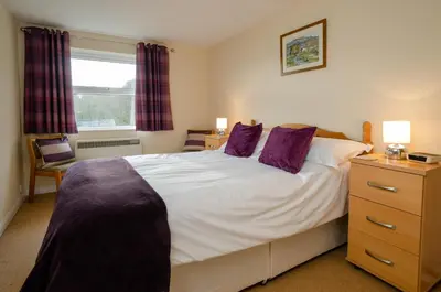 a bedroom with a large white bed with purple pillows at Underthrang, Chapel Stile in Chapel Stile