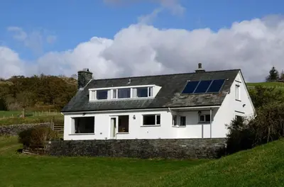 a white house with solar panels on top of a hill at Lang Parrock, Little Langdale in Little Langdale
