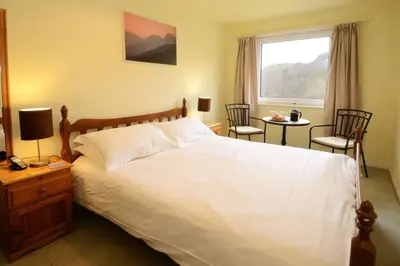 a bedroom with a bed and two chairs and a window at Jadians Nook, 16 Thrang Brow in Chapel Stile