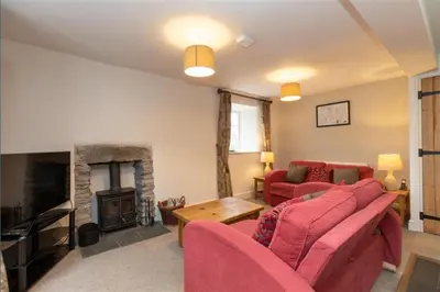 a living room with a red couch and a fireplace at Victory Cottage - Victory Cottage, Cosy village retreat in Chapel Stile