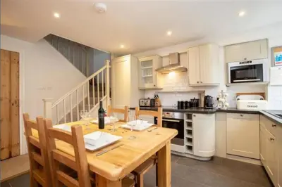 a kitchen with a wooden table with chairs and a kitchen with a counter at Victory Cottage - Victory Cottage, Cosy village retreat in Chapel Stile
