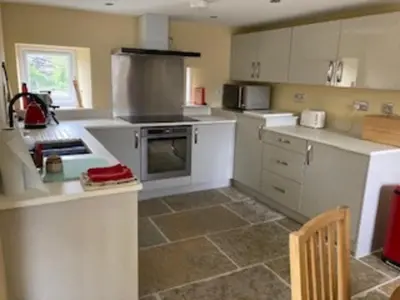 a kitchen with white cabinets and a stove top oven at Cottage at Inch Farm solitude beside the River in Longtown